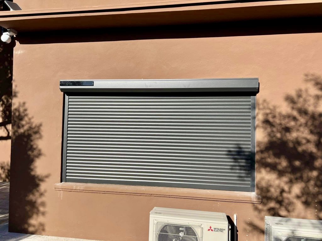 Volet roulant métallique gris sur façade en pierre beige